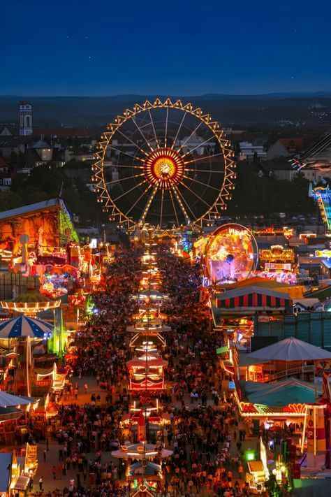 Menschenmengen und beleuchtete Fahrgeschäfte beim Cannstatter Volksfest
