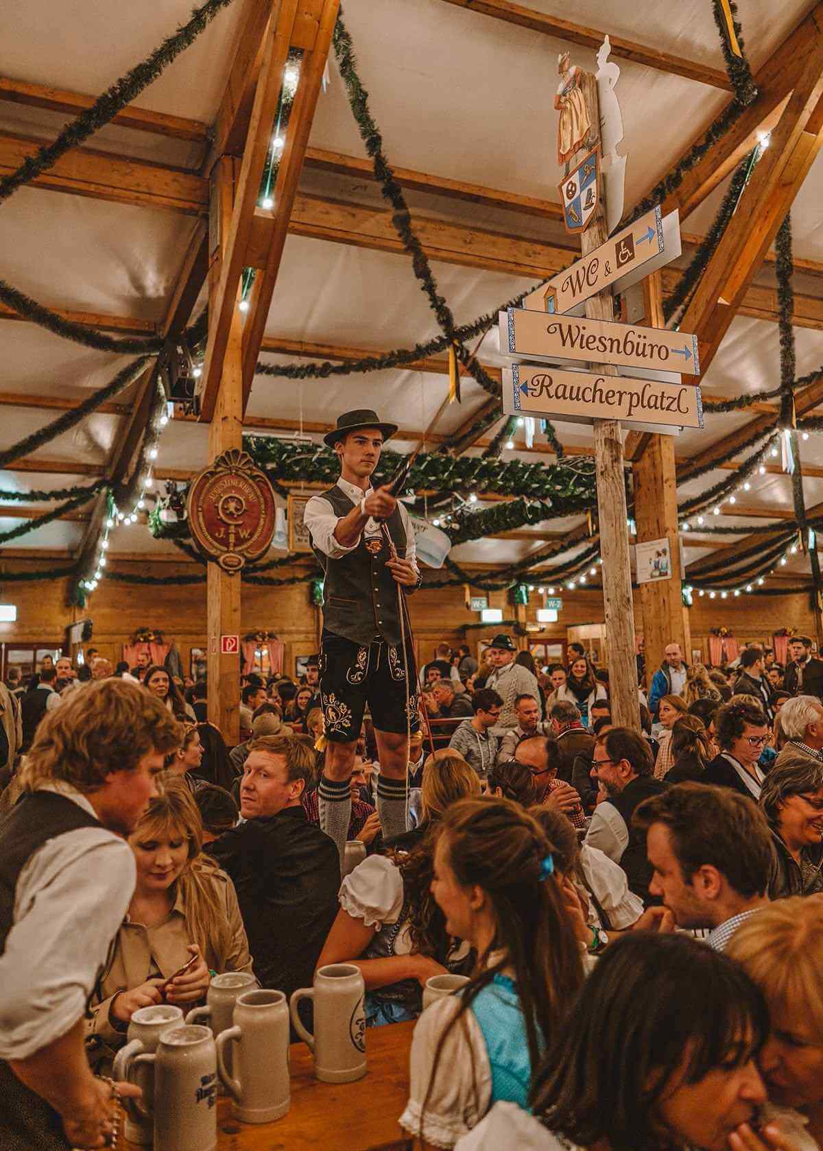 Oktoberfest-Bierzelt mit Menschen, die Krüge heben